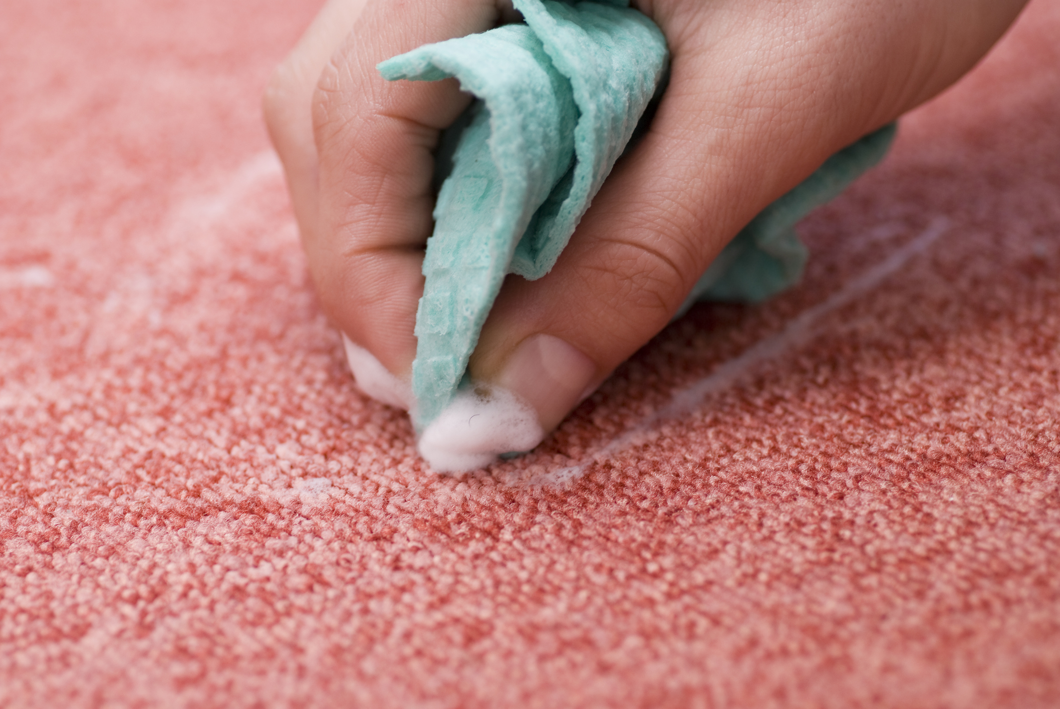 Imagem de um pano úmido limpando um carpete com manchas. 
