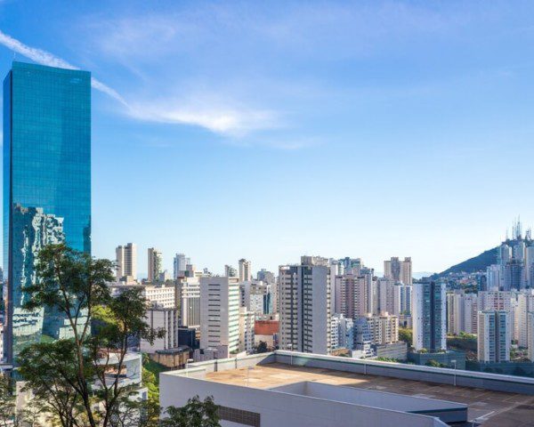 Foto que ilustra matéria sobre as melhores cidades de Minas Gerais mostra uma panorâmica de prédios da cidade de Nova Lima, com destaque para um grande edifício, mais alto, totalmente espelhado