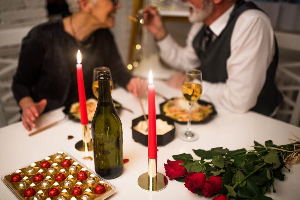 Um casal de idosos estão em um jantar romântico com a mesa decorada para o dia dos namorados.