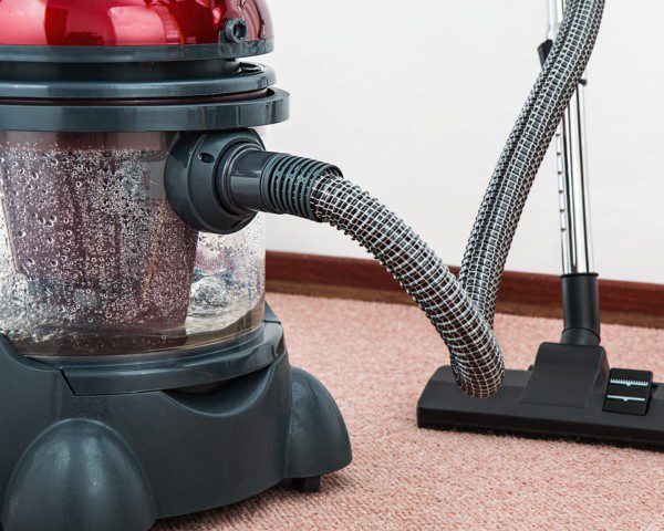 Imagem de um aspirador de pó e água limpando um carpete.
