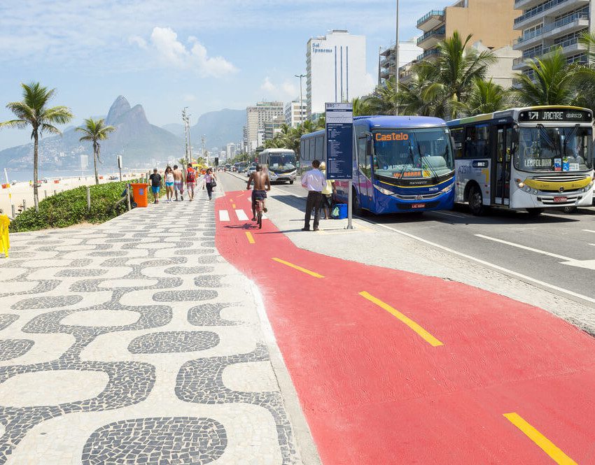 Foto que ilustra matéria sobre o custo de vida no Rio de Janeiro mostra um pedaço do calçadão da Avenida Vieira Souto, em Ipanema à esquerda, com uma pista de ciclovia ao centro e a faixa de tráfego à direita, onde aparecem dois ônibus.