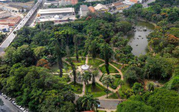 Foto que ilustra matéria sobre os parques em Belo Horizonte mostra uma visão aérea do Parque Municipal Américo Renné Giannetti, com um lago e um coreto cercados por muitas árvores.