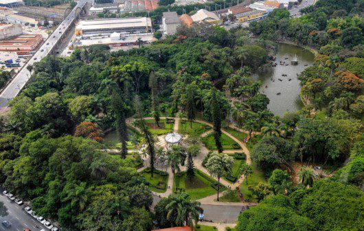 Foto que ilustra matéria sobre os parques em Belo Horizonte mostra uma visão aérea do Parque Municipal Américo Renné Giannetti, com um lago e um coreto cercados por muitas árvores.