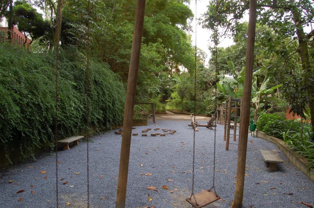 Foto que ilustra matéria sobre parques em Belo Horizonte mostra um playground com balanço, gangorra e ouros brinquedos no Parque Mosteiro Tom Jobim