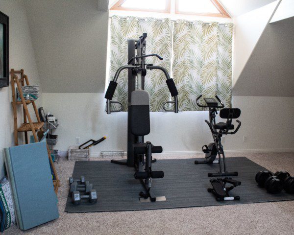 Imagem de uma academia em casa com equipamentos e colchonetes