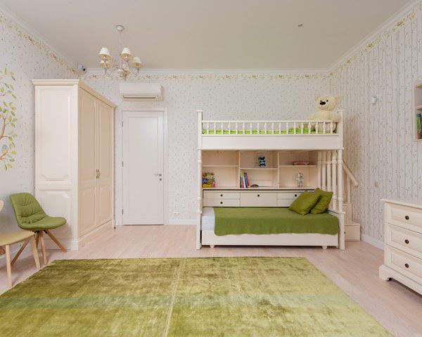 A foto mostra um exemplo de quarto infantil retrô. Com tons de verde e bege, o quarto é composto por um tapete, duas cadeiras, um beliche, uma cômoda e um guarda-roupas. Todos com design retrô.
