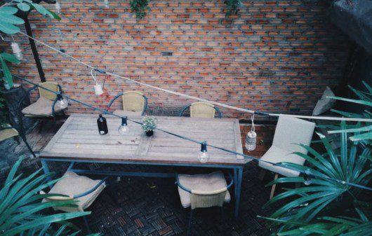 quintal pequeno com mesa de quatro lugares, luzes em fios e plantas