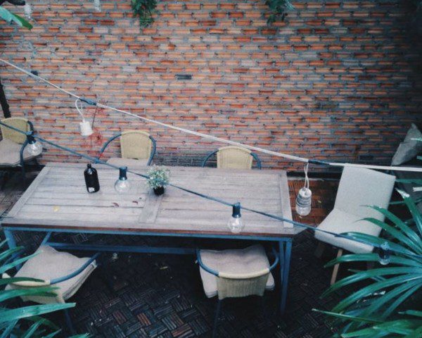 quintal pequeno com mesa de quatro lugares, luzes em fios e plantas