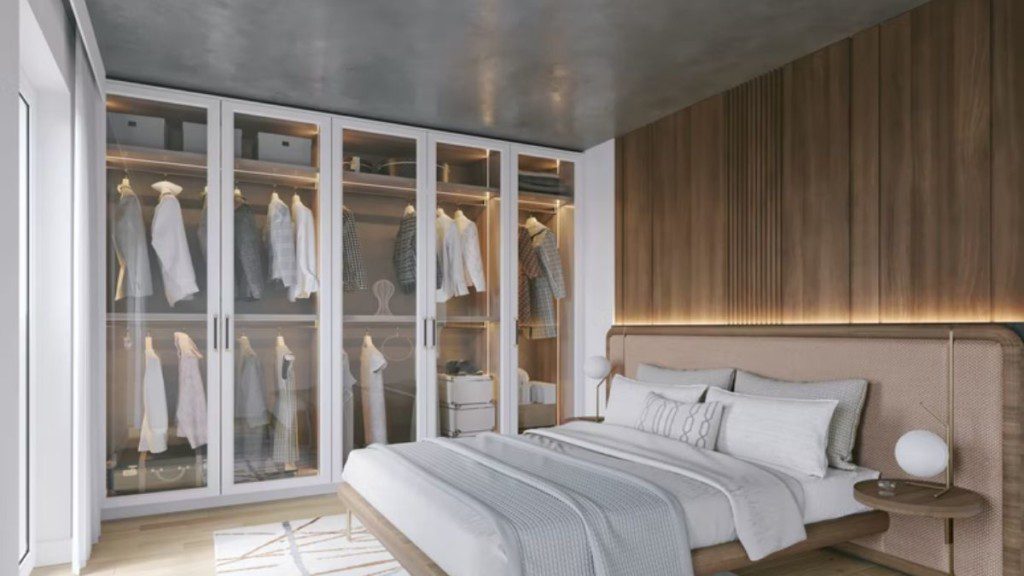armário com portas abertas em um closet de frente para a cama