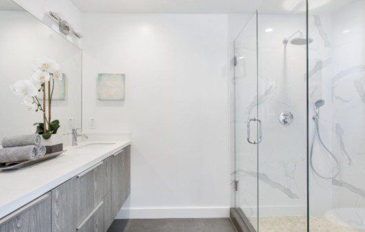 banheiro grande com paredes brancas, móveis claros e boa decoraçao