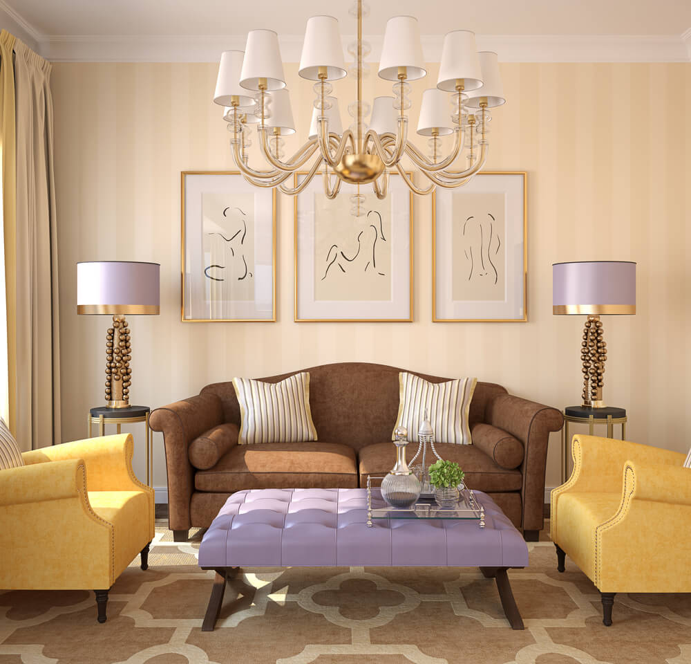 A imagem mostra uma sala com um sofá, duas poltronas, duas luminárias de chão, três quadros que se complementam e um lindo lustre de teto.
