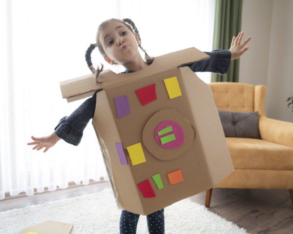 Imagem de uma menina com uma roupa de papelão como brinquedo.