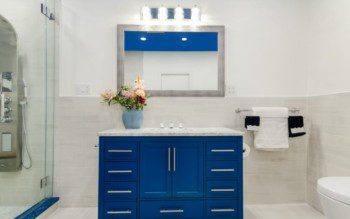 uma das ideias de armário para banheiro, esse em tom azul vivo, contrastando com o branco do ambiente