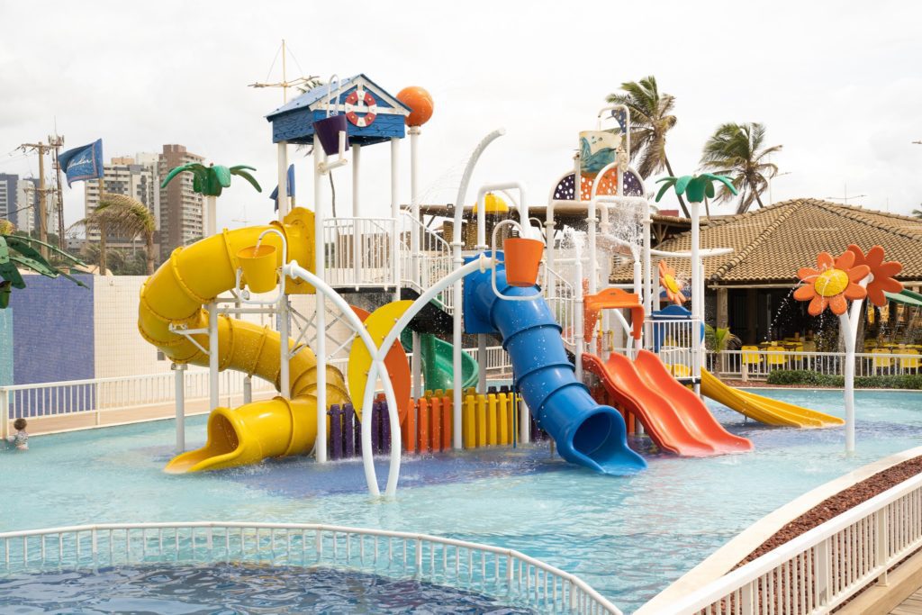 Foto que ilustra matéria sobre parque aquático em Salvador mostra um brinquedo aquático com toboáguas e escorregadores no meio de uma piscina