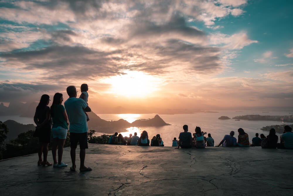 Foto que ilustra matéria sobre Parque em Niterói mostra pessoas admirando o por do sol no alto do Parque da Cidade.