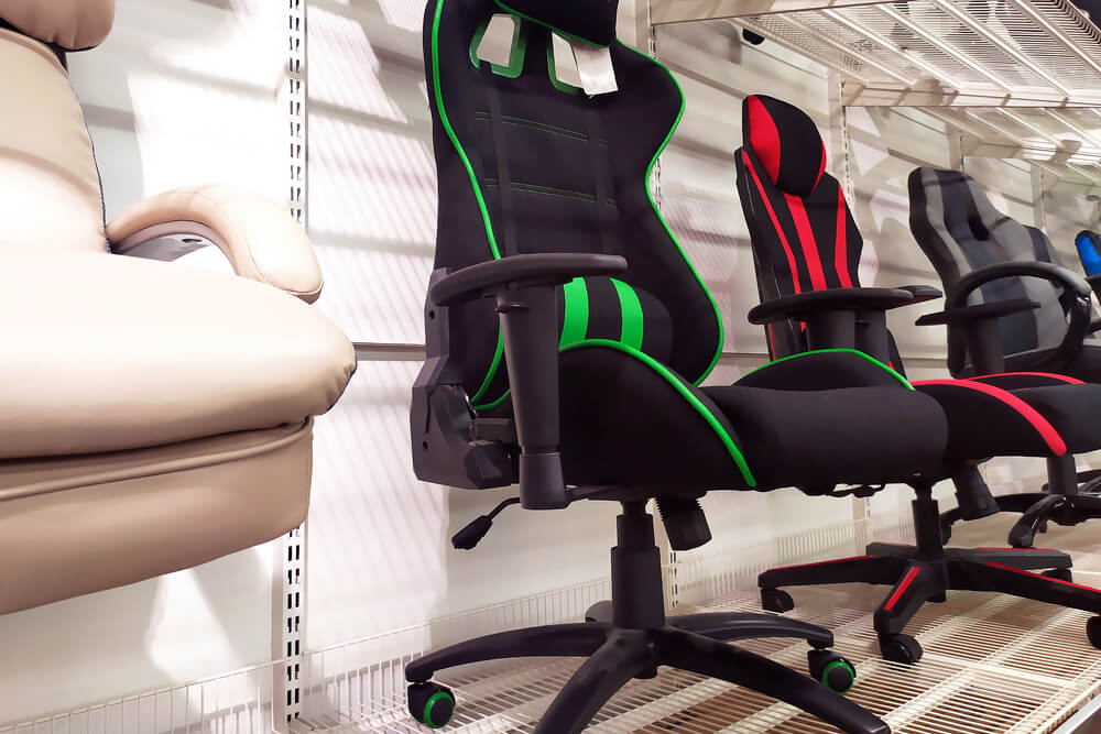 Foto que ilustra matéria sobre sala gamer mostra uma série de cadeiras gamers diferentes, lado a lado, no mostruário de uma loja