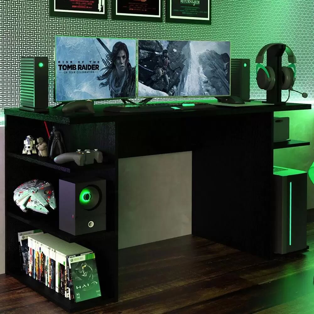 Foto que ilustra matéria sobre sala gamer mostra uma mesa preta de computador, repleta de nichos com brinquedos temáticos de Star Wars nas laterais. Em cima, há dois monitores. E toda iluminação ao redor é verde.
