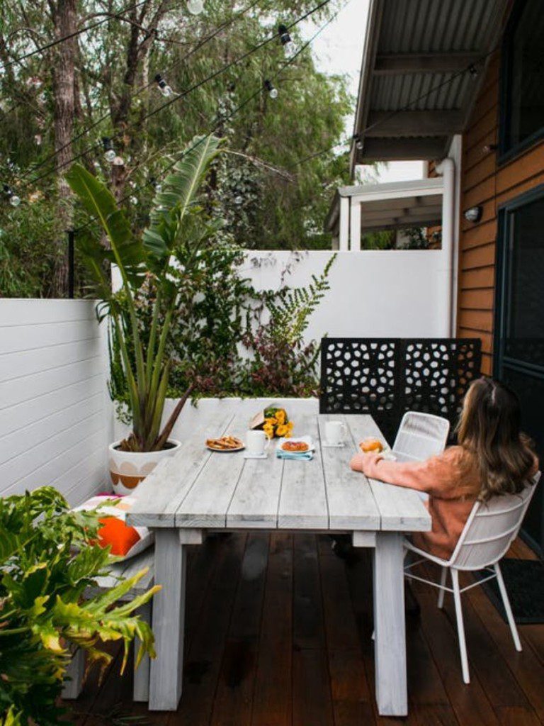 mulher sentada à mesa de uma varanda rústica simples olhando a natureza