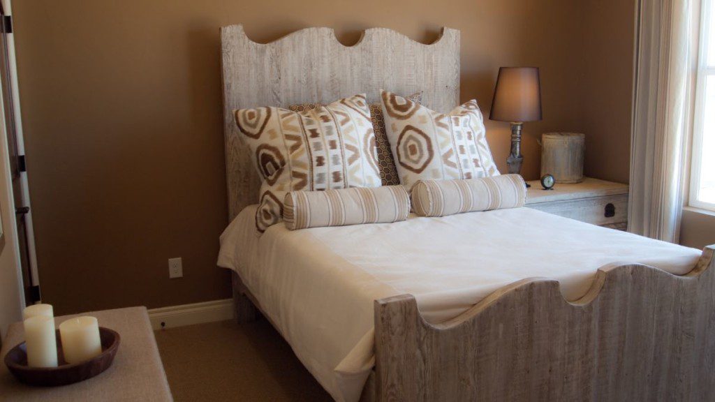 cama com cabeceira rústica, dois travesseiros, mesas de cabeceira e quarto aconchegante