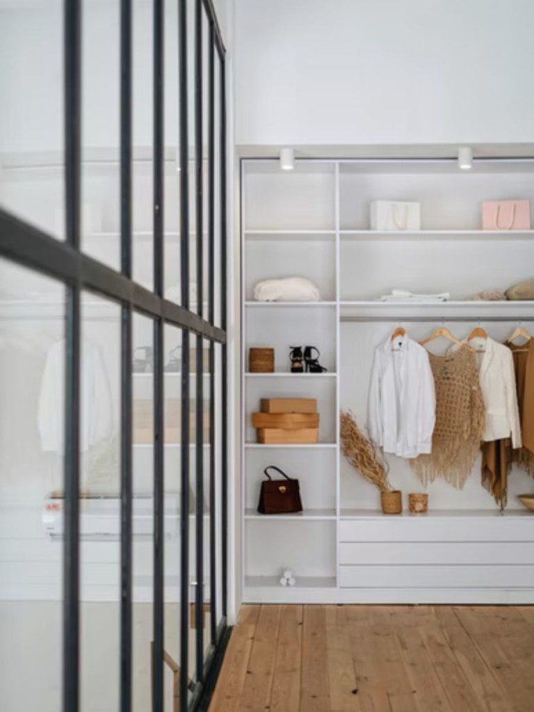closet moderno com iluminação natural e roupas penduradas no armário