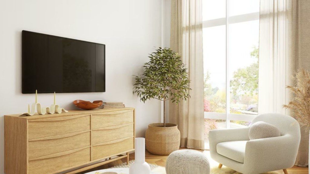 televisão na parede com móvel abaixo dela, e poltronas brancas de frente