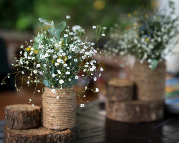 Imagem de um vaso rústico com flores artificiais estilo mosquitinho.