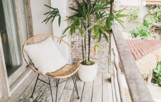cadeira com almofada, plantas em uma varanda rústica