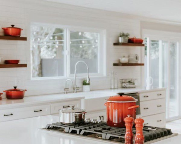 cozinha escandinava com panelas vermelhas e móveis brancos