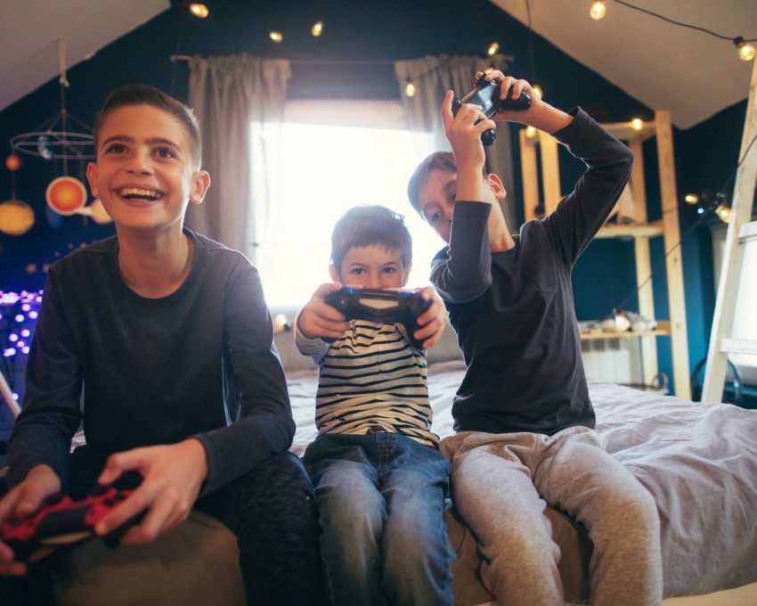 Imagem que ilustra matéria sobre quarto para 3 filhos mostra 3 crianças jogando videogame