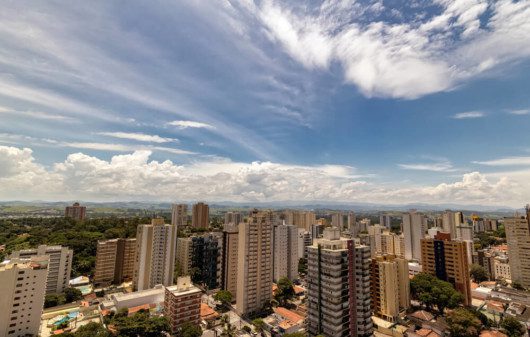 Foto que ilustra matéria sobre custo de vida em São José dos Campos mostra uma visão do alto da cidade, onde aparecem grandes prédios. Ao fundo, um céu azul com algumas poucas nuvens brancas.
