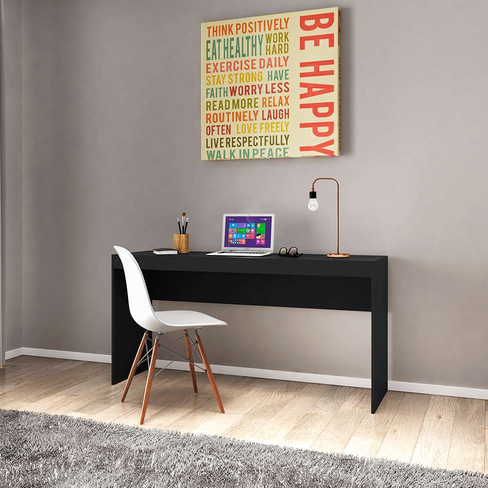 Foto que ilustra matéria sobre decoração de escritório moderno mostra uma mesa preta simples, com um notebook, um par de óculos e uma luminária em cima, encostada em uma parede cinza e com uma cadeira branca à frente
