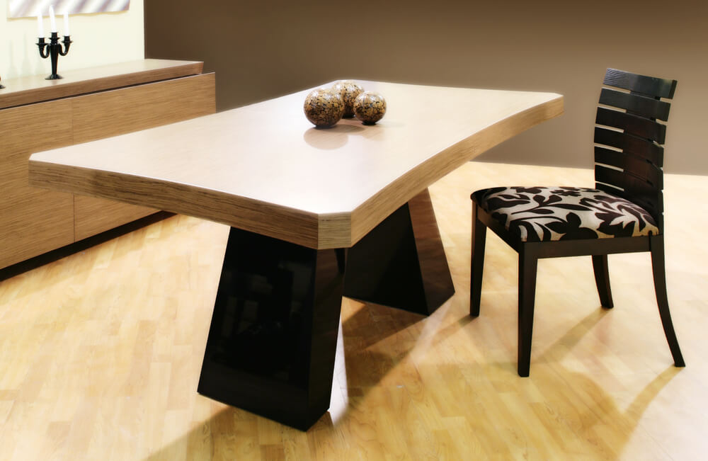 Foto que ilustra matéria sobre decoração de mesa mostra uma mesa com tampo de madeira e apenas uma cadeira ao lado. Sobre ela, três bolas pintadas servem de enfeite como centro de mesa. 