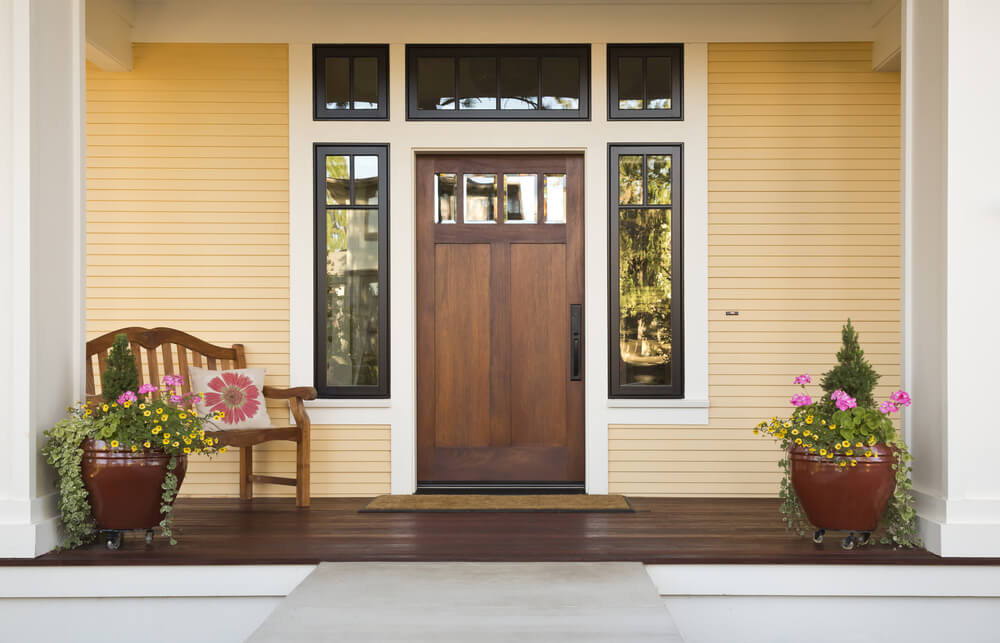 Revestimentos de madeira em uma frente de casa simples dão um tom mais rústico à fachada. No exemplo abaixo, complementado por uma porta de madeira escura, que contrasta com a tinta amarela da madeira.