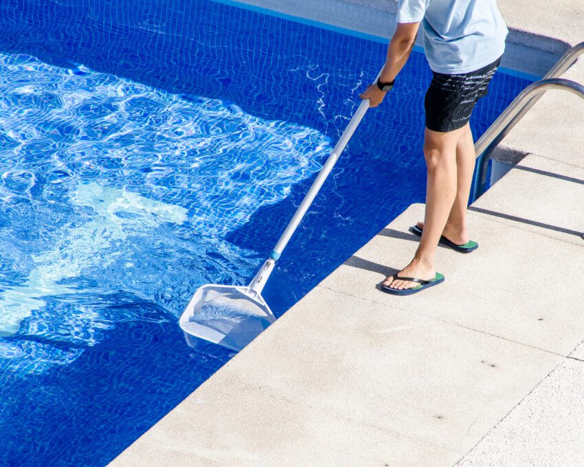 Foto que ilustra matéria sobre como limpar piscina mostra um homem limpando a piscina de casa