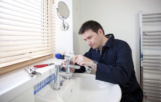 Imagem de um homem consertando uma torneira.