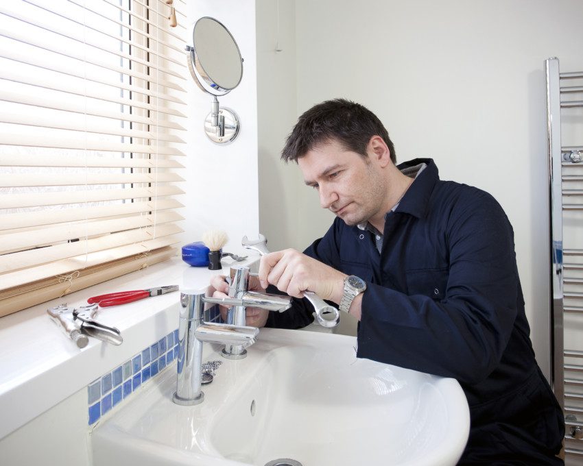 Imagem de um homem consertando uma torneira.
