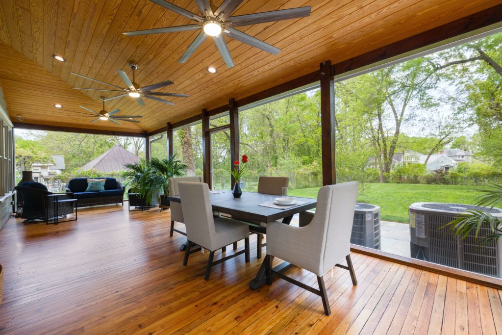 Área gourmet externa com piso de madeira, mesa ao centro e plantas na decoração. Imagem disponível em Pexels.