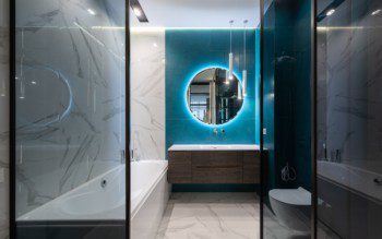 Foto de um banheiro moderno com banheira, espelho redondo, pia com armário embutido e vaso sanitário.