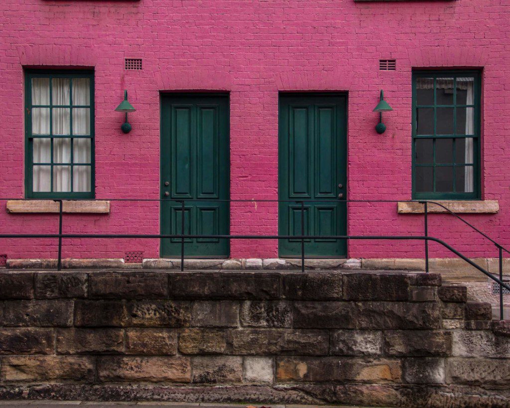 casa com duas portas verdes e cor da parede rosa em tom forte
