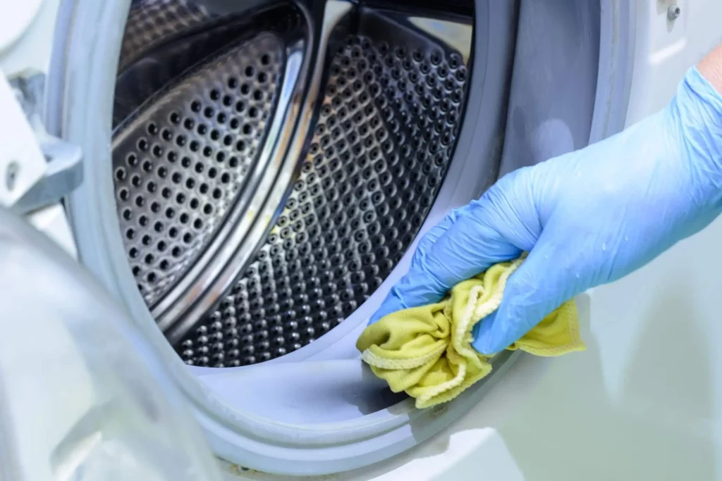 Imagem de uma pessoa limpando a borracha de vedação de uma máquina de abertura frontal para ilustrar matéria sobre como limpar a borracha de vedação da máquina de lavar roupa