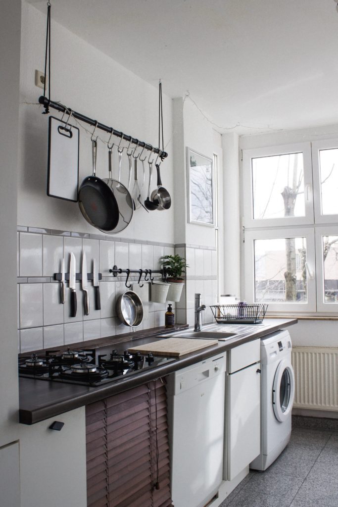 Cozinha e lavanderia integradas com móveis e eletrodomésticos dispostos em corredor. Imagem disponível em Unsplash.