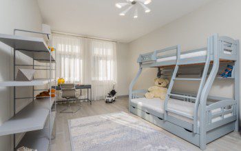 Imagem de um quarto com uma cama beliche, armários e área para estudos.