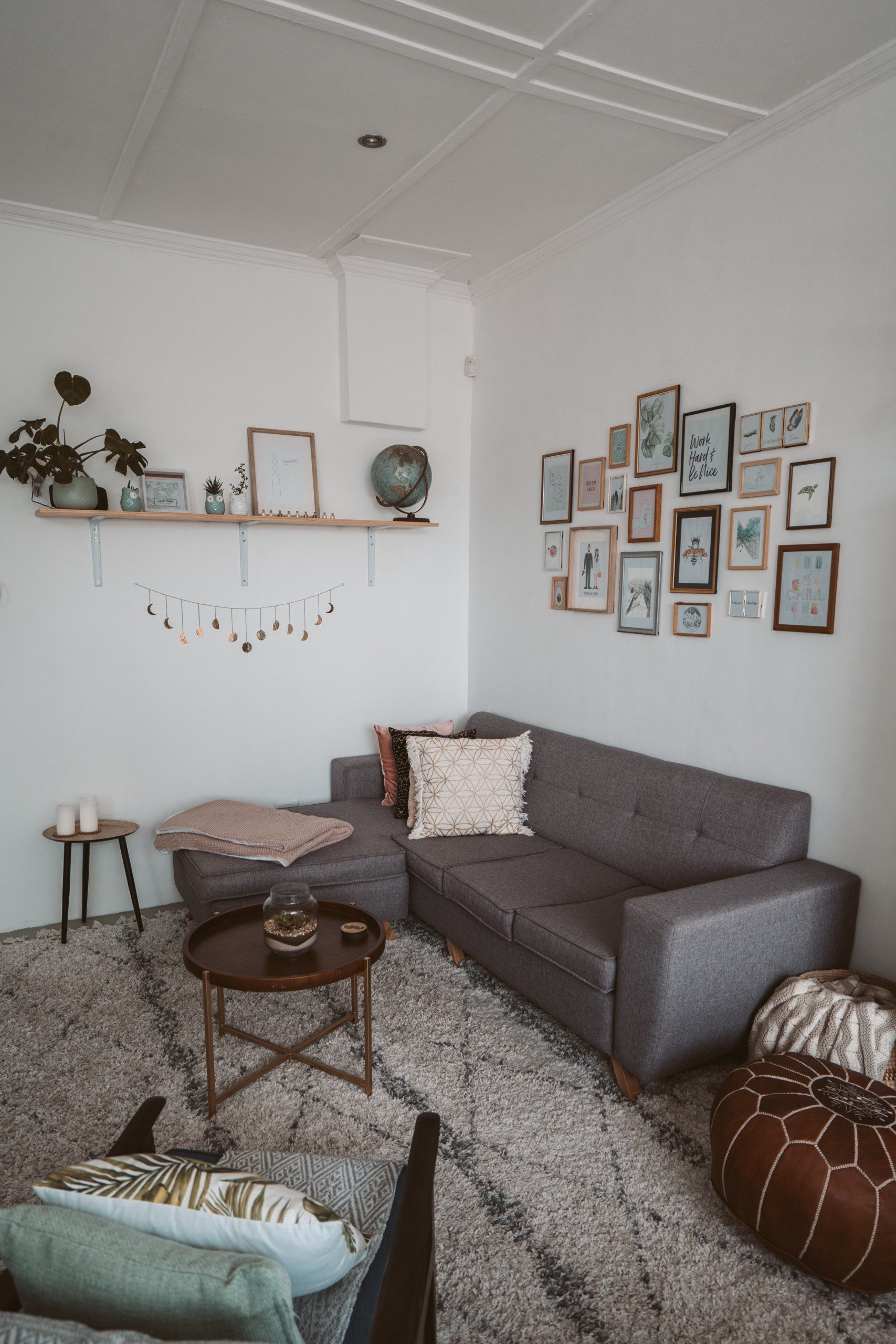 Imagem de uma sala de estar com uma parede com uma composição de diferentes quadros.