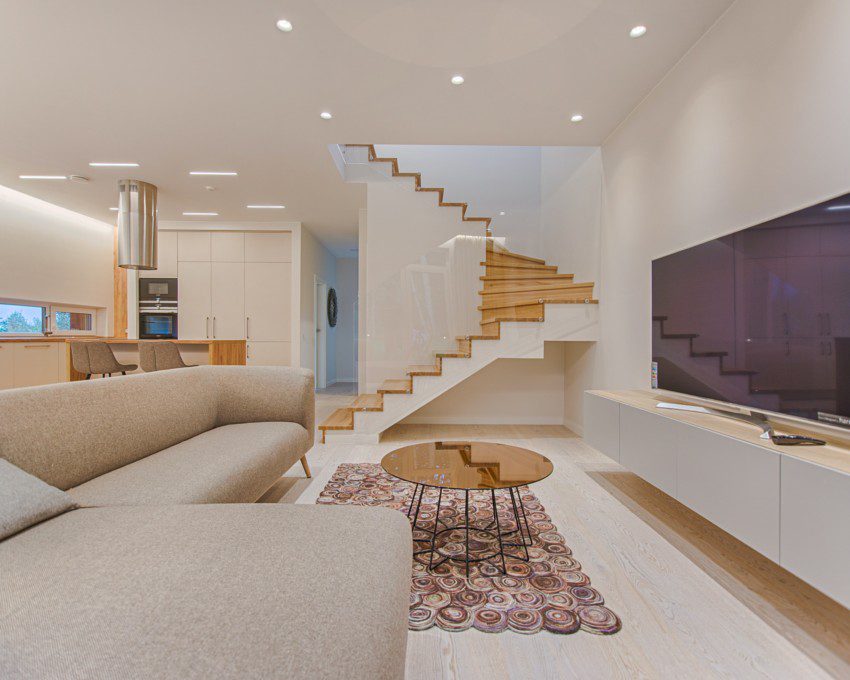 Imagem de uma sala de estar com decoração moderna na cor branca com detalhes em madeira.