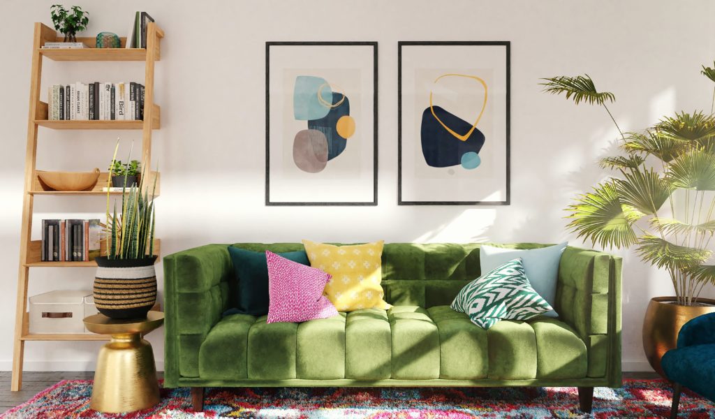 Sala com sofá verde, parede branca, vaso de planta e quadros coloridos.