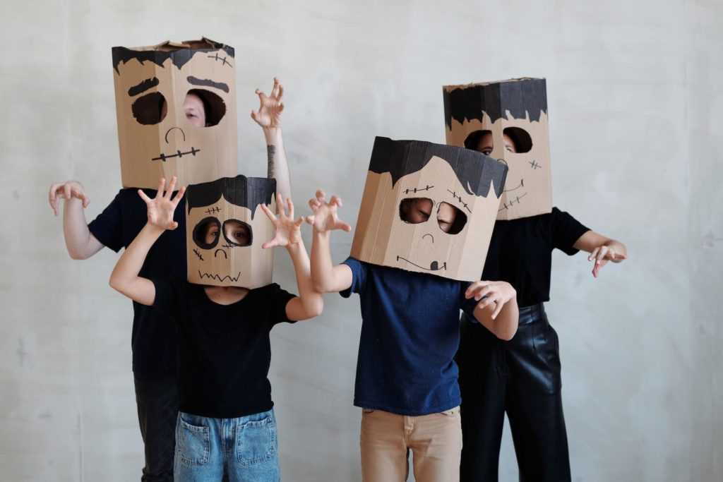 Foto que ilustra matéria sobre decoração de Halloween uma família com dois adultos e duas crianças usando máscaras feitas de papelão