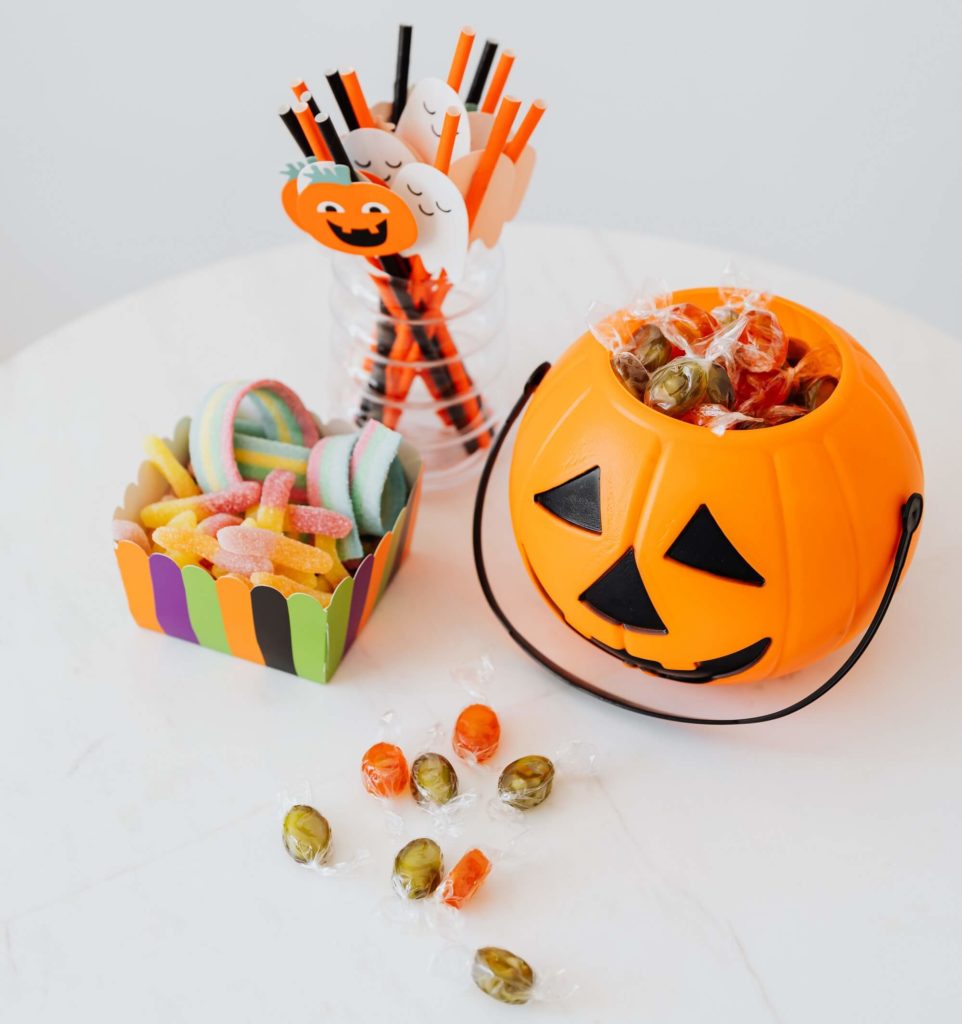 Foto que ilustra matéria sobre decoração de Halloween mostra balinhas coloridas e uma abóbora de plástico com balas dentro.