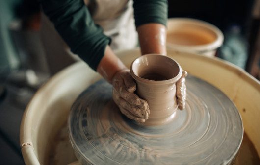 Imagem de uma mulher pintando um vaso de cerâmica para ilustrar conteúdo sobre como fazer vaso de cerâmica.