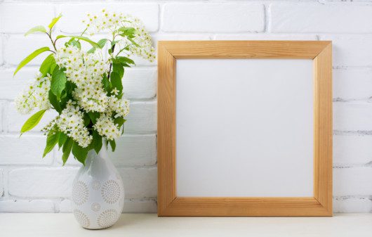 Imagem de um porta retrado com moldura de madeira ao lado de um vaso de flor.