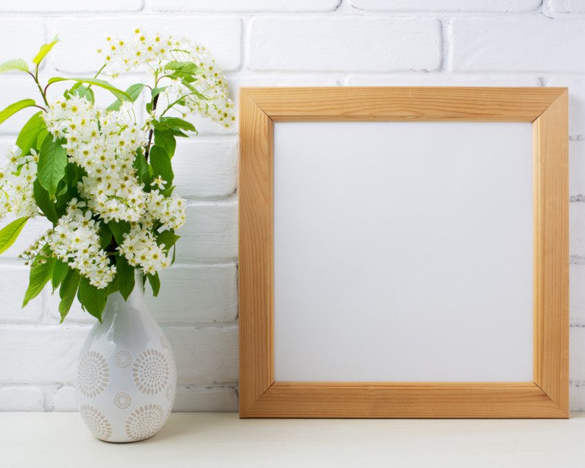 Imagem de um porta retrado com moldura de madeira ao lado de um vaso de flor.